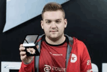 a man in a red jacket is holding a trophy in his hand .