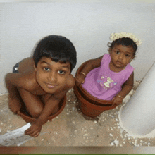 a boy and a girl are kneeling in pots on the floor