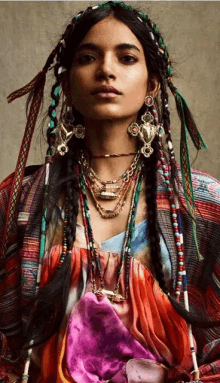 a woman wearing a colorful dress and necklaces with braids in her hair