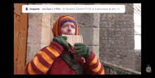 a man in a striped sweater is playing a pan flute with a snapchat icon above him