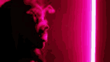 a close up of a person smoking a cigarette in front of a pink light .