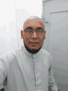 a bald man with glasses and a beard poses for a selfie