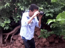 a man in a blue shirt is taking a picture with a camera .