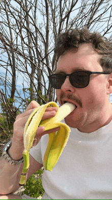 a man with a mustache is eating a banana