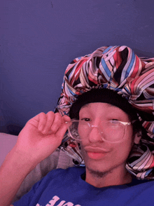 a man wearing glasses and a colorful hat is wearing a blue shirt that says ' i love you ' on it