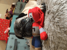 a pug dog laying on a blanket next to a stuffed animal with the letter l on it