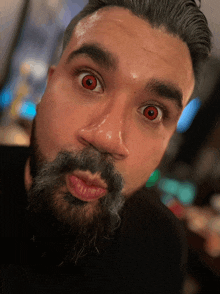 a man with a beard and red eyes is making a face