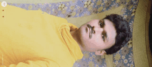 a man in a yellow sweater laying on a bed