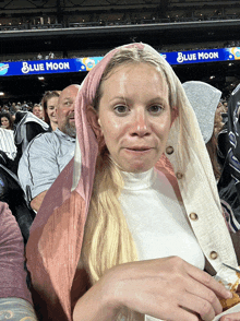 a woman sitting in a stadium with a sign that says blue moon