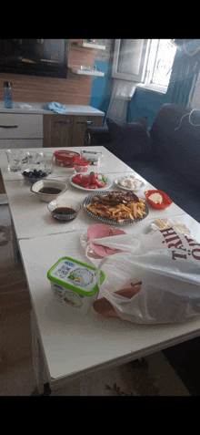 a white table with plates of food and a bag that says ' t.o. ' on it