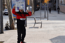 a man standing on a sidewalk with llum bcn written on a sign behind him