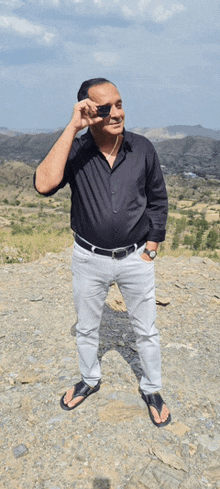 a man in a black shirt and white pants is standing on a hill