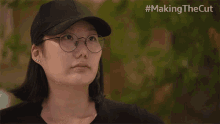 a woman wearing glasses and a baseball cap with the hashtag #making the cut