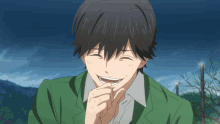 a man in a green jacket is laughing and covering his mouth with his hand