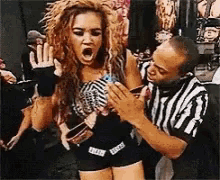 a referee is holding a woman in a wrestling match while she is screaming .