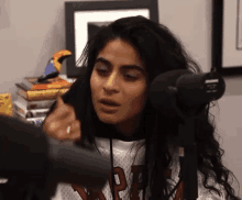 a woman is talking into a microphone while wearing a jersey that says ' nba ' on it .