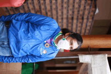 a woman wearing a mask and a blue jacket that says ' ecuador ' on the front