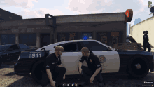 two police officers are kneeling in front of a police car that says 911