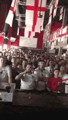 a crowd of people watching a sporting event with flags hanging from the ceiling including one that says ' england '