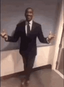 a man in a suit and tie is dancing in a room with his arms outstretched .