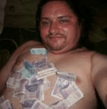 a shirtless man with a lot of money on his chest is taking a selfie .