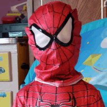 a child dressed in a spiderman costume stands in front of a blue blanket