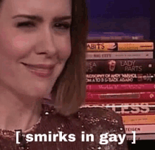 a woman is smiling in front of a stack of books and says i smirks in gay .