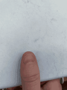 a close up of a person 's finger pointing to a white surface