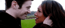 a man and a woman are looking at each other in a field and smiling .