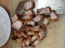 sliced pork on a cutting board next to a knife and a plate