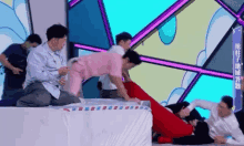 a group of men are playing a game on a stage with a woman in a pink dress .