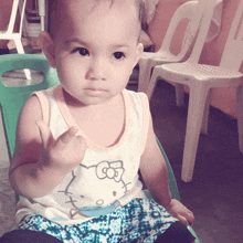 a baby wearing a hello kitty tank top is giving the middle finger