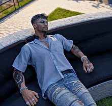 a man laying on a couch with a tattoo on his arm