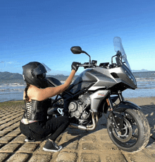 a woman kneeling next to a motorcycle that says ducati