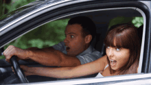 a man and a woman are sitting in a car and the woman is very surprised