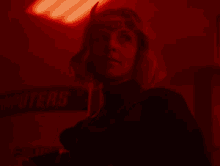 a woman is standing in a dark room in a red light .