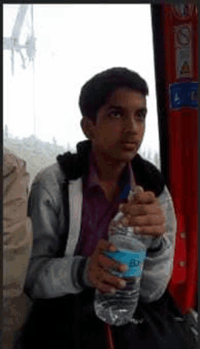 a boy is holding a bottle of water in his hand .