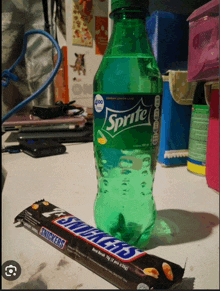 a sprite bottle and a snickers bar on a table