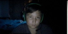 a young boy wearing headphones looks at the camera in a dark room