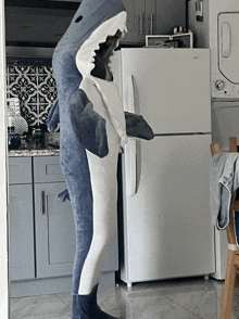 a stuffed shark standing in front of a refrigerator