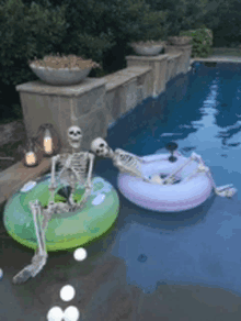 a couple of skeletons are floating in a pool .