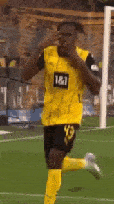 a soccer player wearing a yellow jersey with the number 43 on it is running on the field .