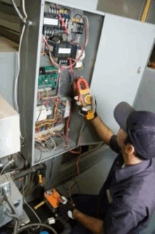 a man is working on a electrical box using a clamp meter