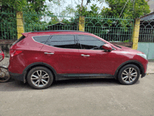 a red suv is parked in front of a fence