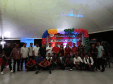 a group of people pose in front of a christmas party sign