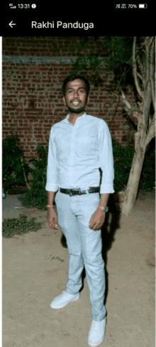 a man in a white shirt is standing in front of a brick wall with the name " rakhi panduga " on the bottom