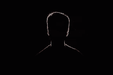 a man 's head is silhouetted against a black background .