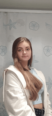 a girl stands in front of a shower curtain with seashells and starfish on it