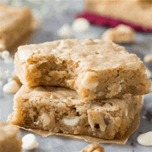 a close up of two white chocolate macadamia nut brownies stacked on top of each other .