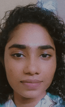 a woman with curly hair looks at the camera with a serious look on her face